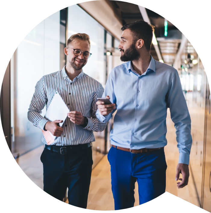 Two business owners talking as they walk through an office corridor.