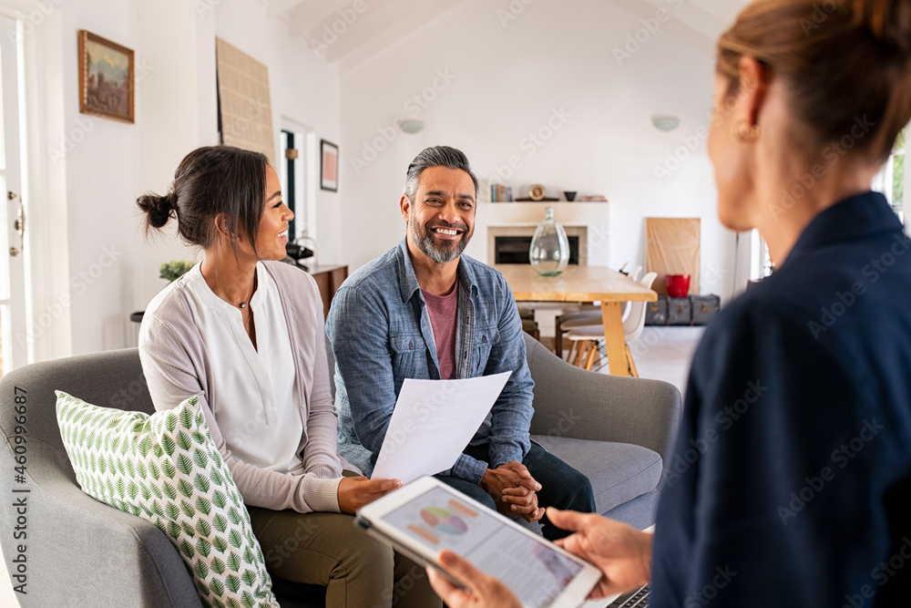 An adviser talking through paperwork and a tablet with a couple in their living room.